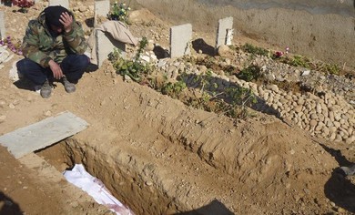 A Free Syrian Army fighter mourns near the grave of his comrade who died in clashes with Assad force