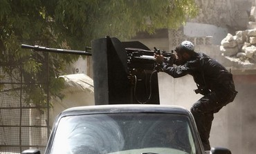 Hassan Jazera, one of the leaders of the Ghurabaa al-sham brigade, aims a mounted weapon in Aleppo