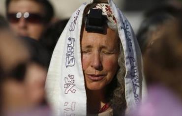 A Women of the Wall member dons tefillin and a tallit.