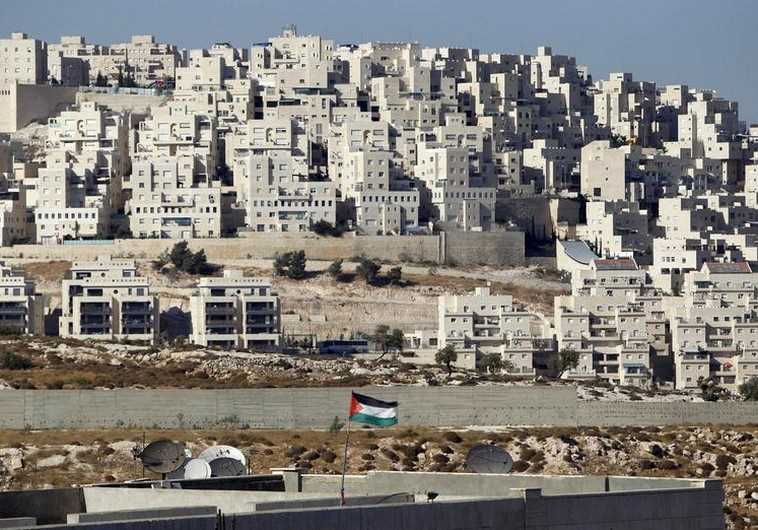 A Palestinian flag flutters in front of the Jerusalem neighborhood of Har Homa