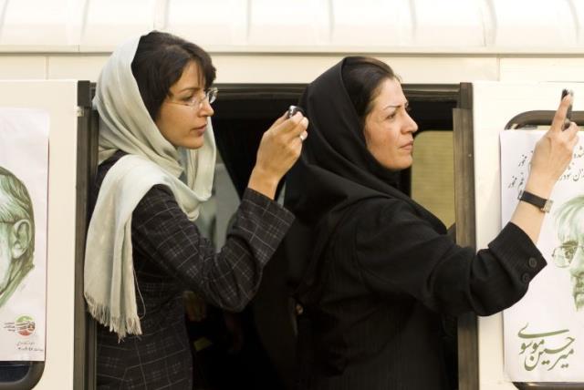 Iranian women take a picture of a presidential candidate with their mobile phones in Tehran , Iran (photo credit: REUTERS)