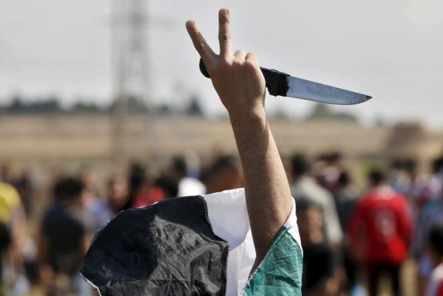 A masked Palestinian protester holds a knife during a protest near the Israeli border fence in northeast Gaza (photo credit: REUTERS)