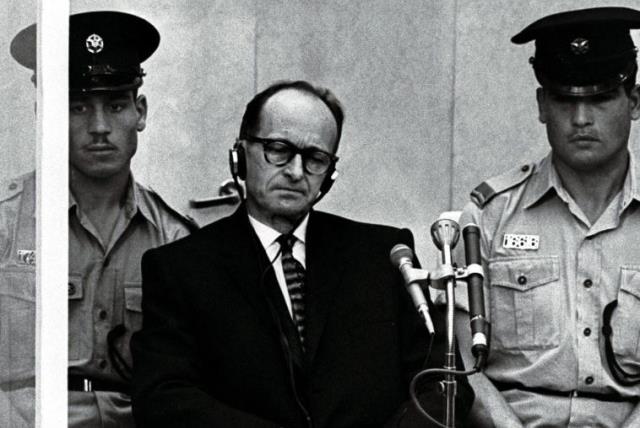 Israeli police flank Adolf Eichmann, the Nazi SS colonel who headed the Gestapo's Jewish Section and was responsible for millions of Jews' deaths in Nazi concentration camps, as he stands trial inside a bulletproof booth in a Jerusalem court (photo credit: REUTERS)