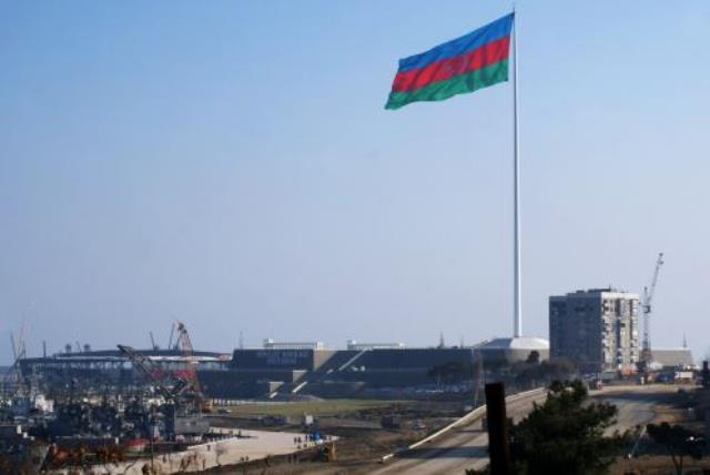 An enormous Azerbaijani flag flies above the construction site of a landmark concert hall on the Caspian Sea shoreline in Baku (photo credit: SAMIR ALIYEV/AFP)