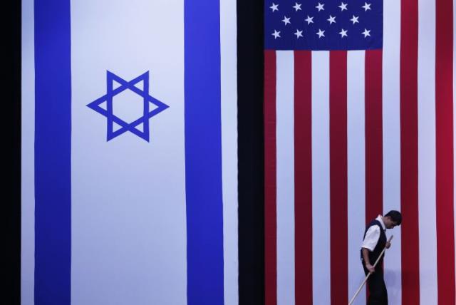 A worker cleans the stage near Israeli and American flags  (photo credit: REUTERS)