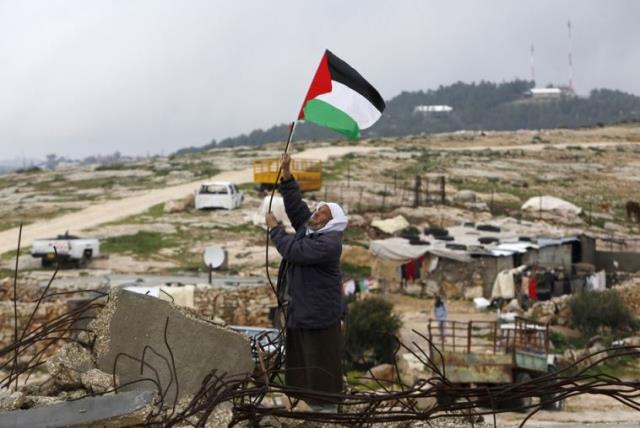 A Palestinian man hangs a Palestinian flag atop the ruins of a mosque, during a snow storm in West Bank village of Mufagara (photo credit: REUTERS)