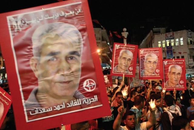 PALESTINIANS HOLD portraits of Ahmed Saadat, leader of the Popular Front for the Liberation of Palestine (PFLP), in Ramallah in 2012 (photo credit: REUTERS)