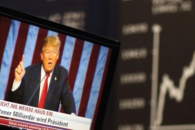 A TV SCREEN showing President-elect Donald Trump is pictured in front of the German share price index, DAX board, at the stock exchange in Frankfurt, Germany, in November (photo credit: REUTERS)