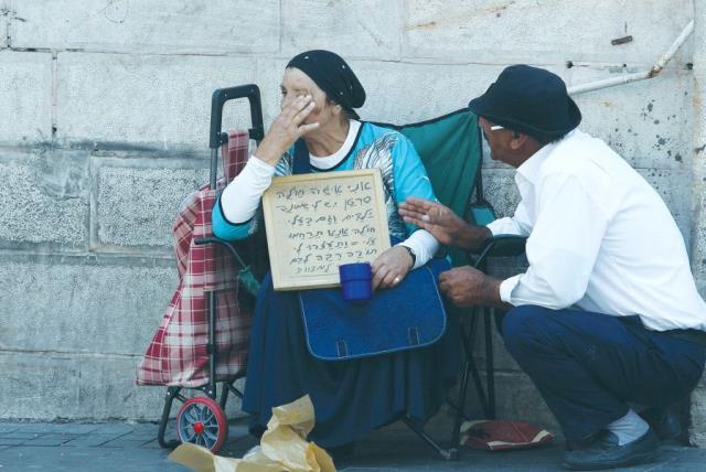 A PASSERBY stops to console a poor woman in Jerusalem in 2015. (photo credit: MARC ISRAEL SELLEM)