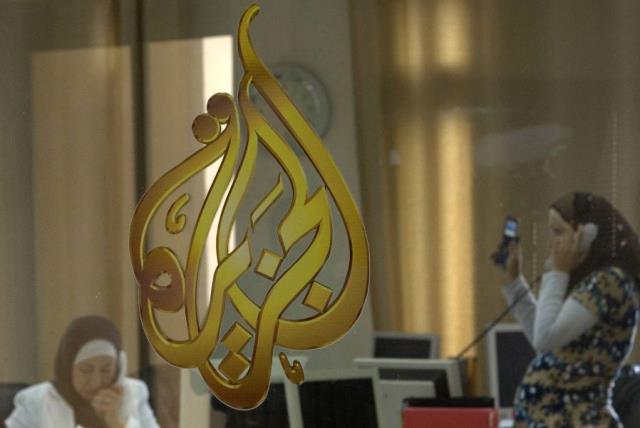 Palestinian journalists are seen through a glass window at the offices of the Arabic news channel Al-Jazeera in the West Bank city of Ramallah July 15, 2009. (photo credit: REUTERS)