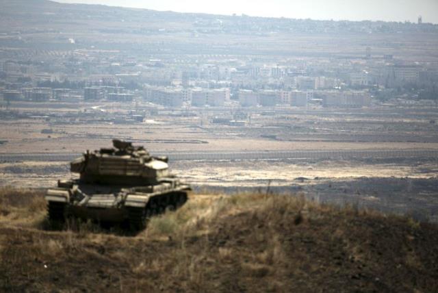 The Syrian area of Quneitra is seen in the background as an out-of-commission Israeli tank parks on a hill, near the ceasefire line between Israel and Syria, in the Golan Heights. (photo credit: BAZ RATNER/REUTERS)