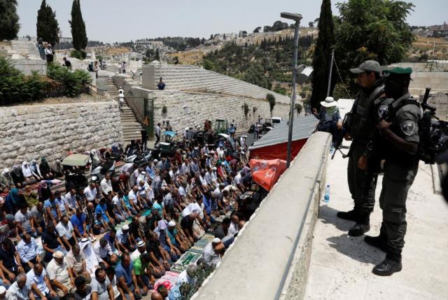 Israeli border police officers stand guard as Palestinians pray at Lions' Gate, the entrance to Jerusalem's Old City, in protest over Israel's new security measures at the Temple Mount July 20, 2017. (photo credit: REUTERS)