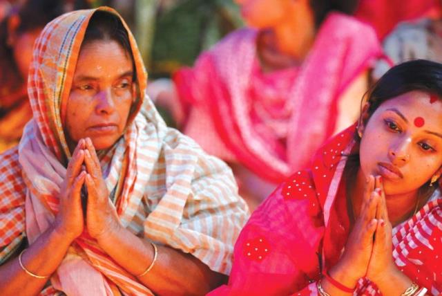 HINDU DEVOTEES sit together on the floor of a temple to observe Rakher Upabash for the last day, in Dhaka, B (photo credit: REUTERS)