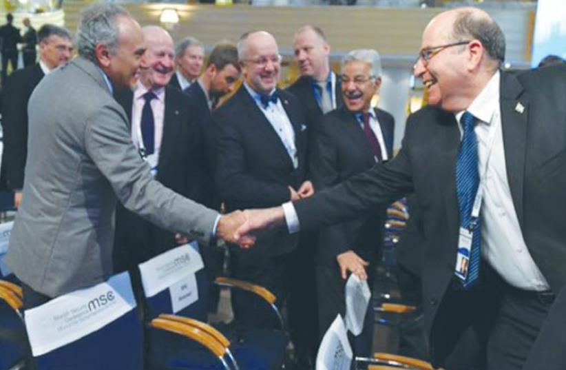 DEFENSE MINISTER Moshe Ya’alon (right) reaches out to Saudi Arabia’s Prince Turki al-Faisal in Munich yesterday. (photo credit: TWITTER)