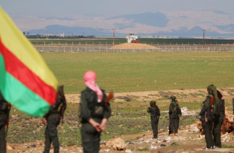 Kurdish members of the Self-Defense Forces stand near the Syrian-Turkish border in the Syrian city of al-Derbasiyah, February 9, 2016. (photo credit: RODI SAID / REUTERS)