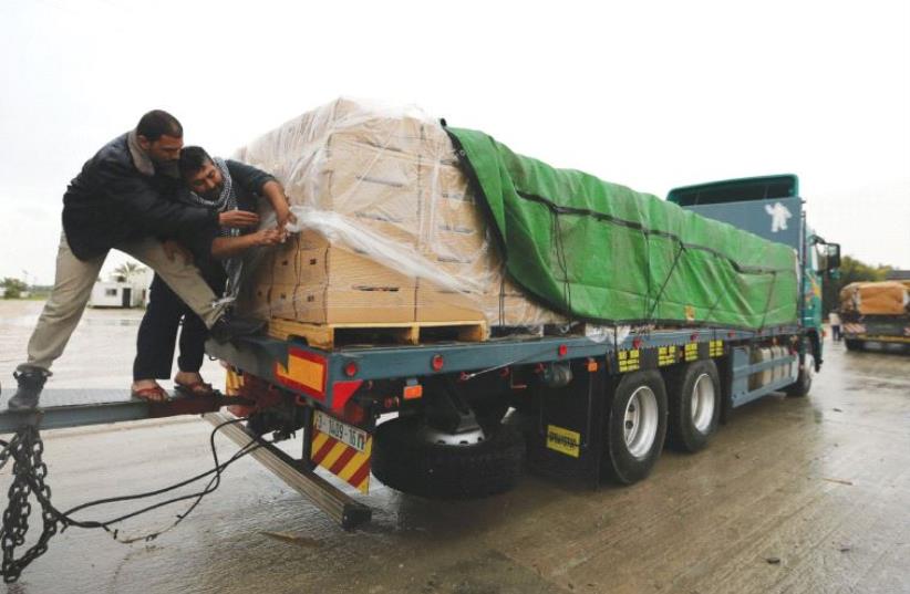 PALESTINIANS COVER cartons containing vegetables before exporting them to Israel, at the Kerem Shalom crossing in Rafah in the southern Gaza Strip in 2015. (photo credit: IBRAHEEM ABU MUSTAFA/REUTERS)