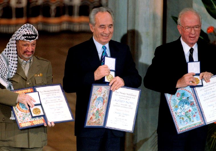 Former PLO chairman Yasser Arafat, then foreign minister Shimon Peres and then prime minister Yitzhak Rabin (from L to R) show their shared Nobel Peace Prize awards to the audience in Oslo on December 10, 1994 (photo credit: REUTERS)