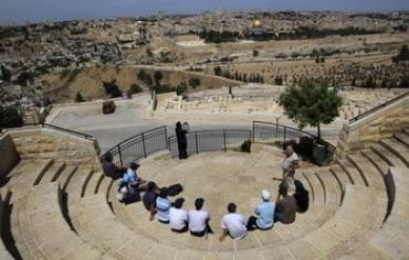 Tourists sit at a lookout point on the Mount of Olives, overlooking Jerusalem's Old City.