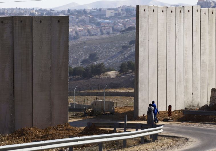 Palestinians walk near an opening in Israel's security fence in the east Jerusalem neighborhood of A-tur (credit: REUTERS)
