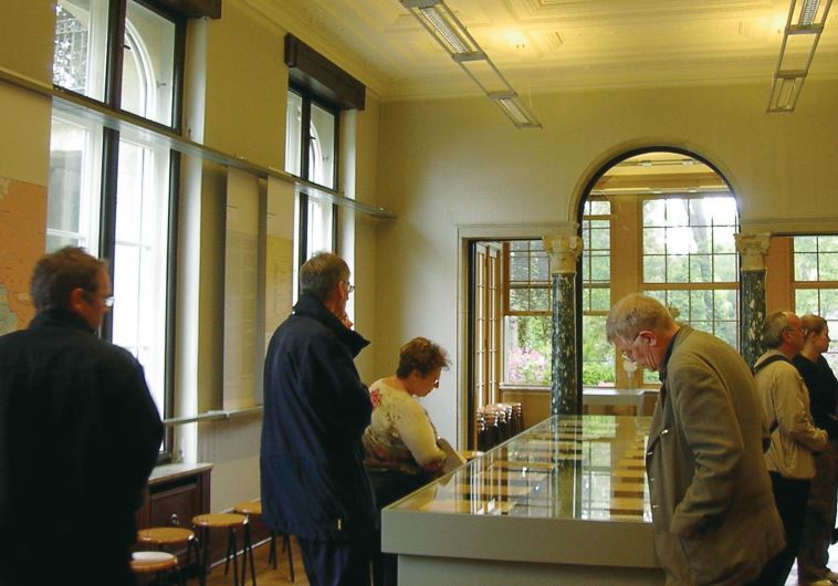 Visitors to the Wannsee House look at copies of the meeting’s minutes in the conference room. (credit: Wikimedia Commons)