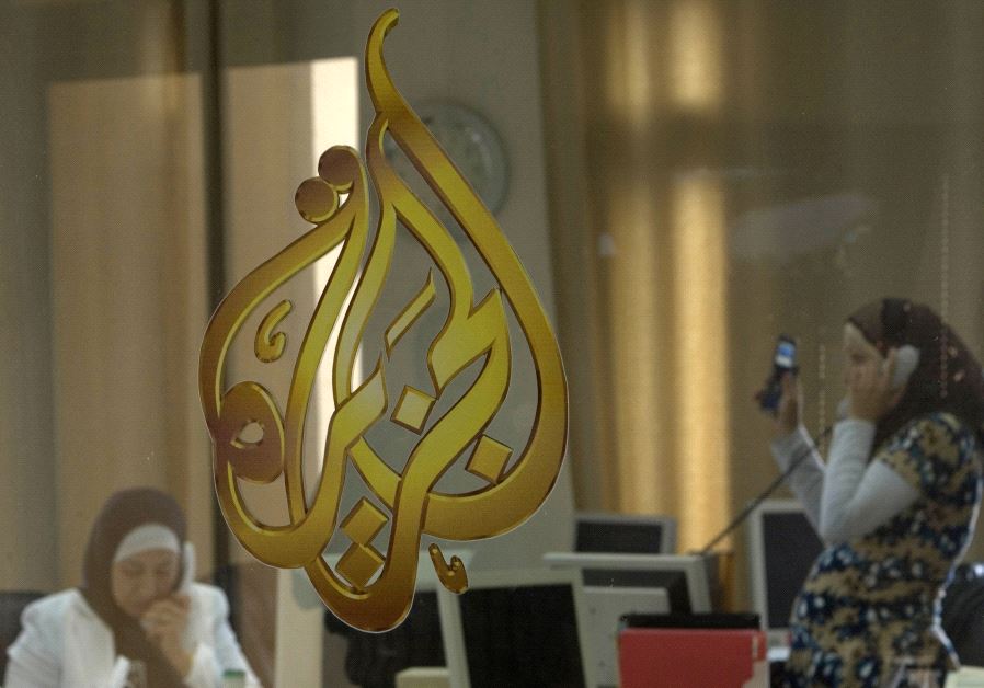 Palestinian journalists are seen through a glass window at the offices of the Arabic news channel Al-Jazeera in the West Bank city of Ramallah July 15, 2009. (credit: REUTERS)